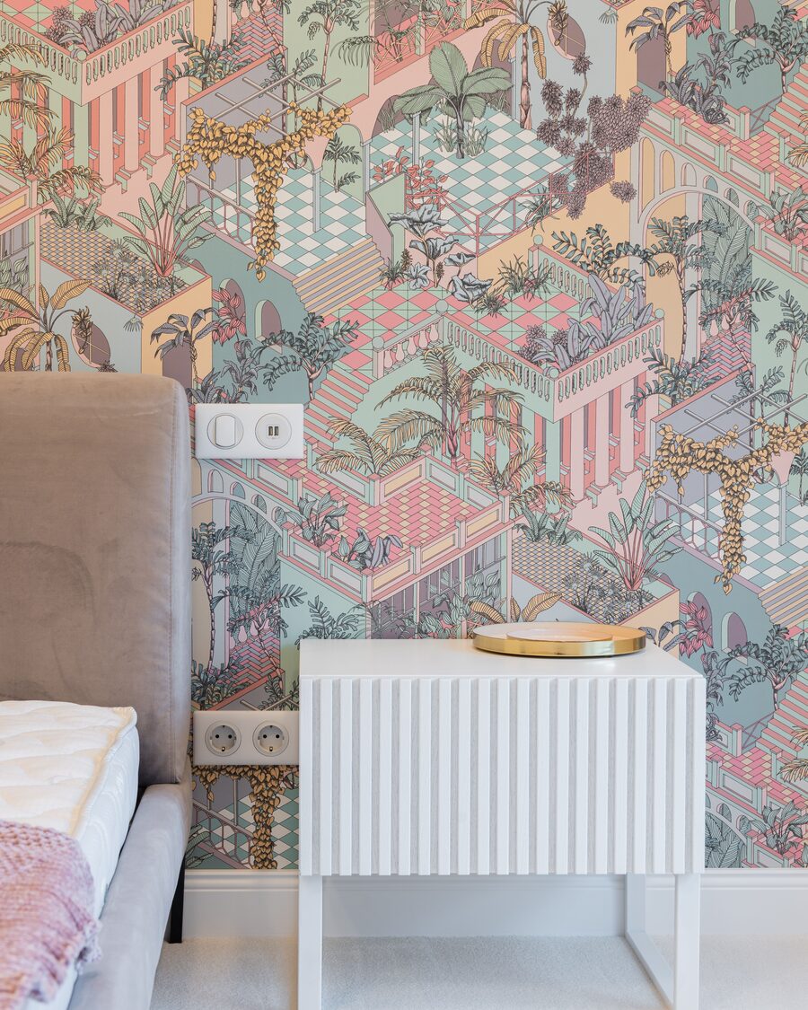 Bedroom corner with a pastel illustrated garden wallpaper, a taupe upholstered headboard and a white fluted nightstand