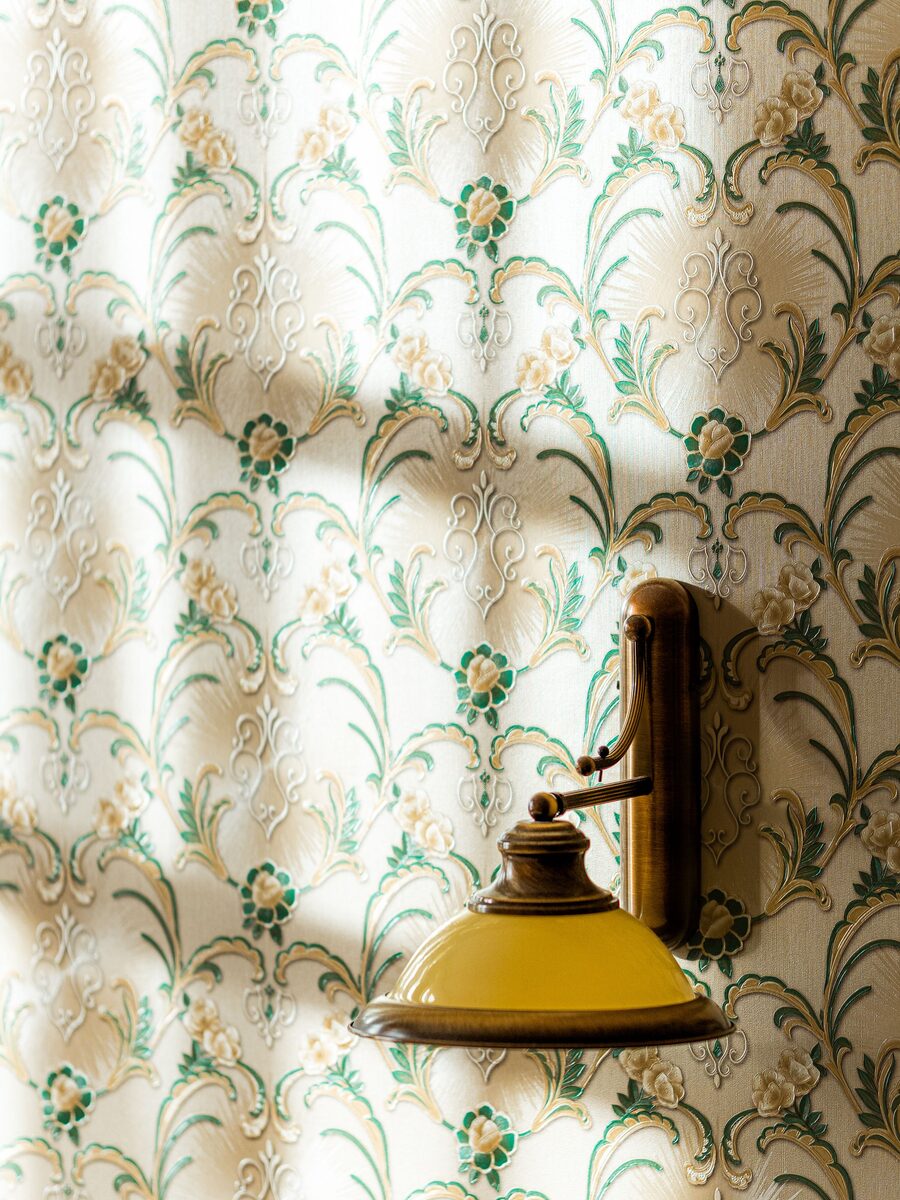 Brass and amber glass wall sconce mounted cleanly on a cream, green and gold damask floral wallpaper
